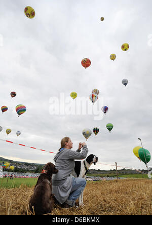 A young woman takes pictures of hot air balloons taking off into the sky at the start of more than 150 hot air balloons at the hot air balloon festival 'Montgolfiade 2012' in Warstein, Germany, 1 September 2012. More than 343 pilots with 206 balloons from 11 countries are taking part at this year's 22nd Montgolfiade, which is considered to be Europes largest hot air balloon festiva Stock Photo