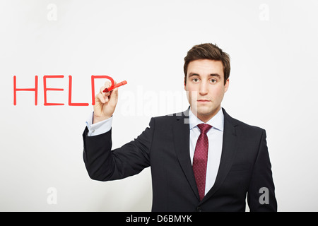 Businessman writing ?help in air Stock Photo