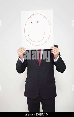 Businessman holding happy face over his face Stock Photo