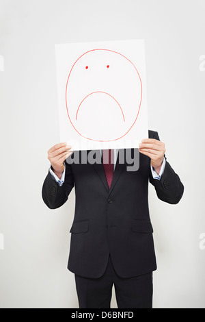 Businessman holding sad face over his face Stock Photo