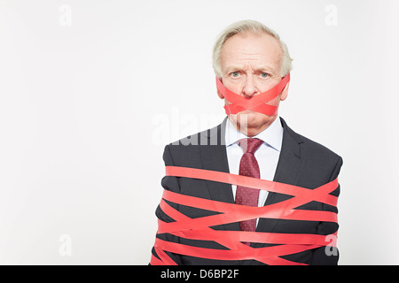 Businessman wrapped in red tape Stock Photo