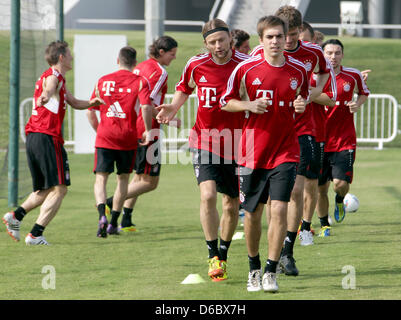 Anatolij Timoschtschuk (from L), Philipp Lahm and Thomas Mueller from FC Bayern Munich warm up on the practice field at the team's training camp in Doha, Qatar, 03 January 2012. From 02 until 09 January 2012, Bundeliga team FC Bayern Munich is training for the second half of the season in the Gulf state of Qatar. Photo: KARL-JOSEF HILDENBRAND Stock Photo