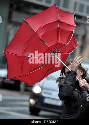 A woman fights against hurricane-force winds with her umbrella in the city centre of Frankfurt Main, Germany, 05 January 2012. With wind speeds of more than 110 km per hour storm front 'Andrea' causes trouble in Germany. Photo: Boris Roessler Stock Photo