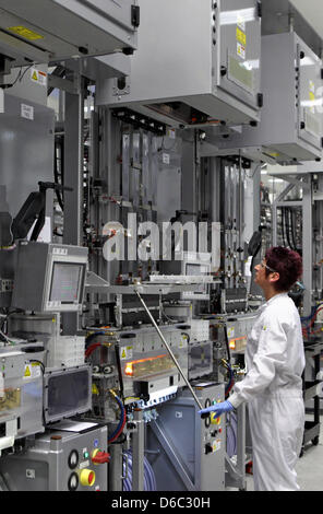 An employee of the solar company Sovello controls the production of polycrystalline silicon wafers in Bitterfeld-Wolfen, Germany, 11 January 2012. The company announced new investments into the expansion of their factory today. Capacity of wafer production will be increased to 1000 with 200 new ovens. Around 35 million euros are to invested by 2013. The company produces solar cells Stock Photo