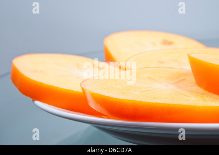 Cuted persimmon few pieces on plate Stock Photo