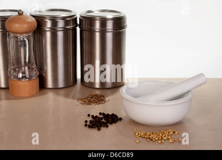 Mortar and pestle with spices containers and a peppermill in the background Stock Photo