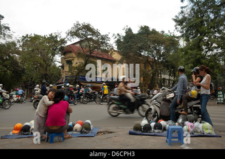 Horizontal view of street vendors selling crash helmets at busy junction with lots of mopeds, criss crossing in all directions Stock Photo