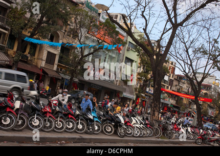 Horizontal view of lots of mopeds, the favoured form of transport in Vietnam parked on the side of the road. Stock Photo