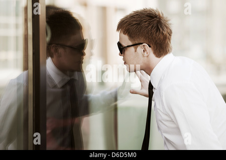 Young businessman looking through a window Stock Photo