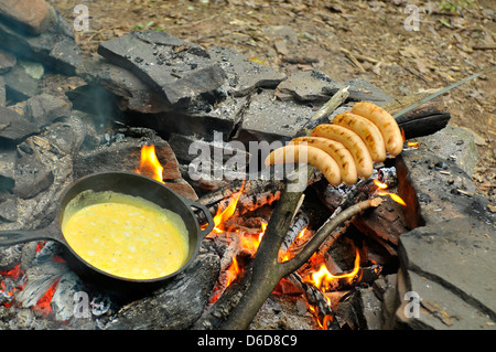 fried eggs on fire at iron fried pan with grilled sausages on skewer Stock Photo