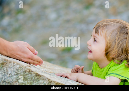 Father reaches out her baby on a rock Stock Photo
