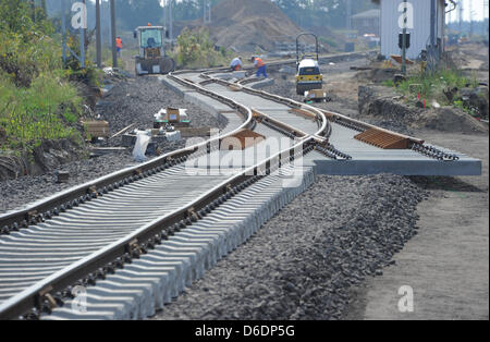 Workers work behind an already finished track section in Loewenberg, Germany, 10 September 2012. Until April 2013, the route between Berlin and rostock will be closed. At three track sections, sleepers, tracks and ballast will be renewed. It is the declared goal to decrease the travel time between Berlin and Rostock to under two hours until December 2013. Photo: Bernd Settnik Stock Photo