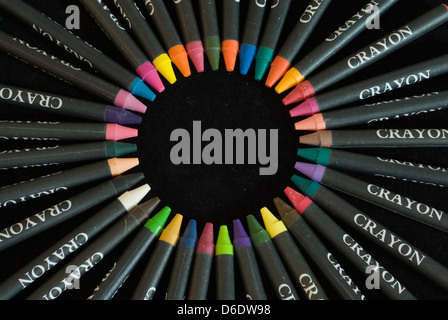 Close up on a circle created in the center of a circle of colorful children's crayons, isolated on a black background Stock Photo