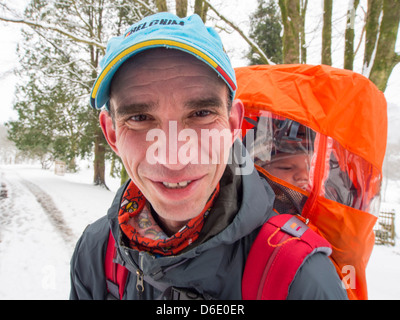 Phil Craker carries his baby through the snow in ambleside in the Lake district, during the extreme winter weather, Stock Photo