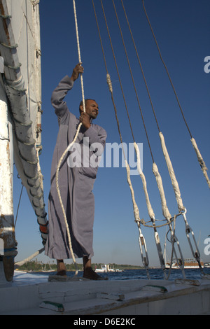 Felucca boatman on the River Nile Egypt pulling rope and raising sail Stock Photo