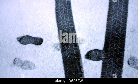 Traces of a predestrian cross tracks of a car on a thin layer of fresh snow in Stuttgart, Germany, 20 January 2012. Mild weather is expected in the coming days. Photo: Bernd Weissbrod Stock Photo