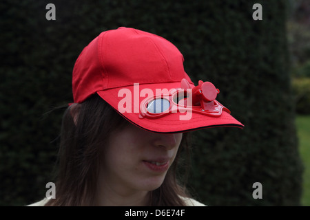 Woman Wearing Red Baseball Cap With Solar Powered Fan Stock Photo