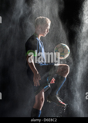 Caucasian soccer player kicking ball in rain Stock Photo