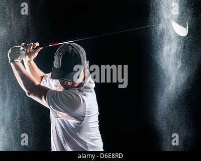 Asian golf player swinging club in rain Stock Photo