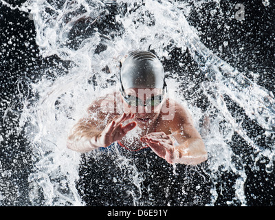 Caucasian swimmer splashing in water Stock Photo