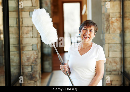 Smiling Hispanic woman holding duster Stock Photo