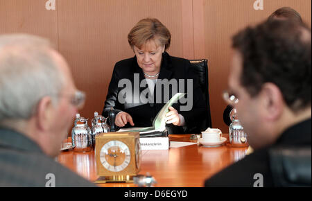 German Chancellor Angela Merkel (CDU) is pictured at the start of the cabinet meeting at the Federal Chancellery in Berlin, Germany, 01 February 2012. In the foreground German Minister of Finance Wolfgang Schaeuble (CDU, L) and German Minister of the Interior  Hans-Peter Friedrich can be seen talking. Photo: WOLFGANG KUMM Stock Photo