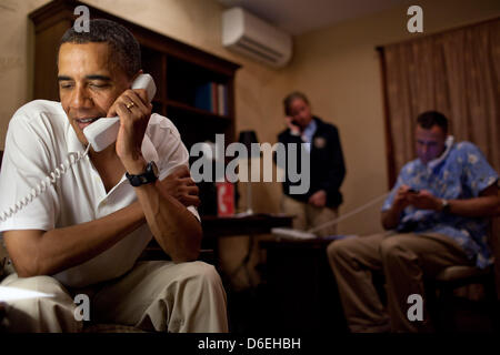 United States President Barack Obama makes phone calls to 10 American service members stationed around the world, from his vacation rental home in Kailua, Hawaii, December 24, 2011. White House Communications Agency (WHCA) Presidential Communications Officer CPT Mallory Fritz and Military Aide Lieutenant Colonel Sam Price coordinate the calls in the background. Mandatory Credit: Pe Stock Photo