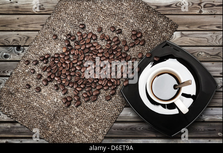 Cup of espresso coffee with beans and canvas on weathered wooden table Stock Photo