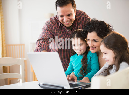 Family using laptop together at table Stock Photo
