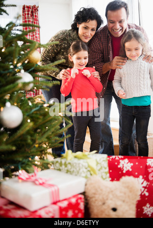 Family examining presents under Christmas tree Stock Photo