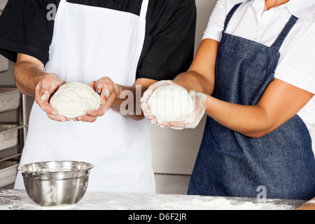 Chefs Presenting Dough In Kitchen Stock Photo