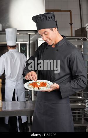 Chef Garnishing Dish In Kitchen Stock Photo