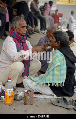 A barber giving his customer a wet shave amongst a row of squatting barbers in a street in Old Delhi, India. Stock Photo