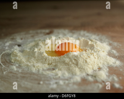 Egg broken into a well of flour Stock Photo