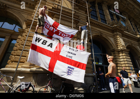 England supporters leverage scaffolding at the main train station in Frankfurt to raise flags during the 2006 FIFA World Cup. Stock Photo