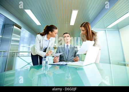 Inspirated boss sitting at workplace surrounded by two secretaries Stock Photo