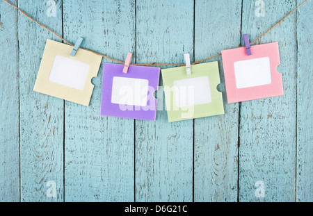 Four empty colorful photo frames or notes paper hanging with clothespins on wooden blue vintage shabby chic background Stock Photo