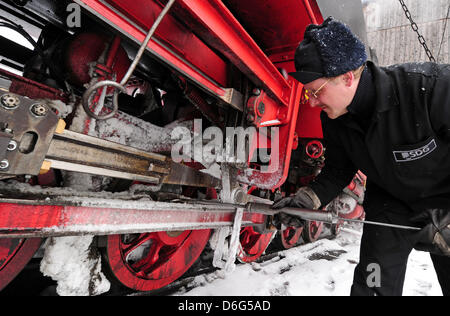Fireman Jens Koch makes preparations at the lokomotive of the Fichtelbergbahn - the mountain railway of the Fichtel mountain - shortly before the next travel in Oberwiesenthal, Germany, 09 February 2012. With the beginning of winter holidays, it is likely that many families will enjoy the 115-year-old railway running between Cranzahl and the highest city in Germany at the Fichtelbe Stock Photo