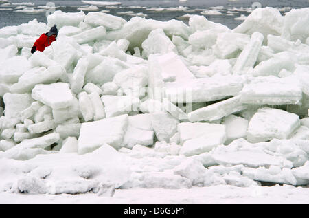 A woman climbes through a landscape of piled up sheets of ice on a beach along the Baltic Sea near Thiesseow, Germany, 10 February 2012. The recent strom in northern Germany has caused sheets of ice to pile up to meter high mountains of ice on the island of Ruegen. Meteorologists forecast more frosty temperatures to dominate the weather in the state of Mecklenburg-Western Pomerania Stock Photo