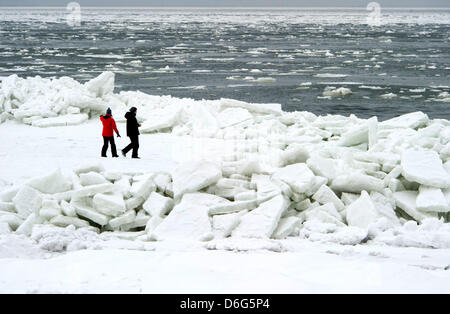 A tourist couple trudges through a bizzare landscape of piled up sheets of ice on a beach along the Baltic Sea near Thiesseow, Germany, 10 February 2012. The recent strom in northern Germany has caused sheets of ice to pile up to meter high mountains of ice on the island of Ruegen. Meteorologists forecast more frosty temperatures to dominate the weather in the state of Mecklenburg- Stock Photo