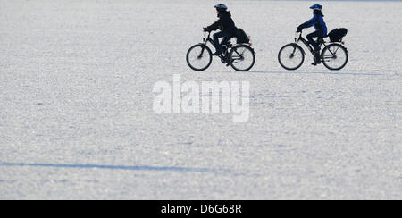 Two school children ride their bikes across the the frozen Maschsee Lake seen from the new city hall in Hanover, Germany, 10 February 2012. Thousands of people are expected out on the frozen lakes this weekend. Photo: JULIAN STRATENSCHULTE Stock Photo