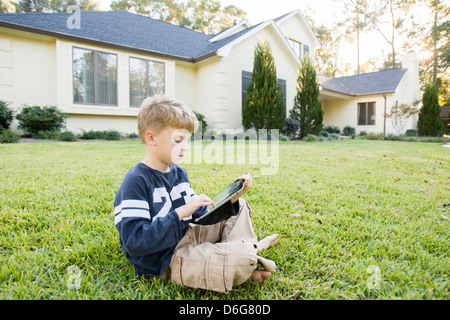 Caucasian boy using digital tablet on lawn Stock Photo