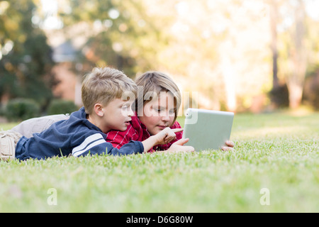 Caucasian boys using digital tablet on lawn Stock Photo