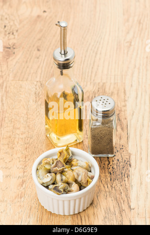 A portion of fresh whelks that are ready to eat with a bottle of vinegar and some ground pepper. Stock Photo