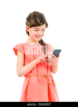Smiling little cute girl in red dress playing on mobile smartphone. Isolated on white background. Stock Photo