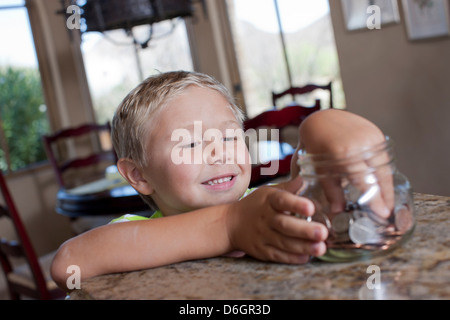 Boy putting savings in glass jar Stock Photo
