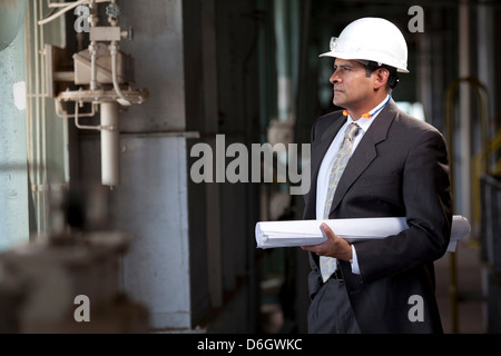 Businessman with blueprints in plant Stock Photo