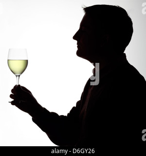 Silhouette portrait of a young man enjoying a glass of white wine Stock Photo