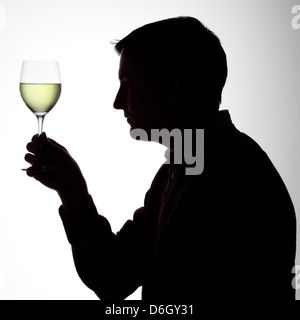 Silhouette portrait of a young man enjoying a glass of white wine Stock Photo