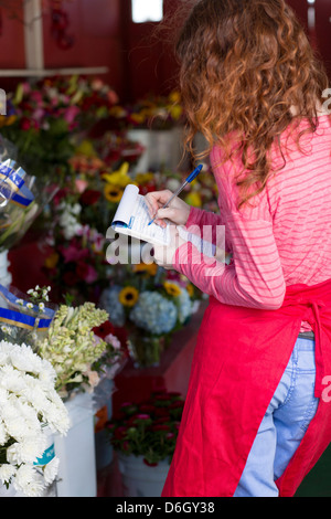 Florist making notes in shop Stock Photo